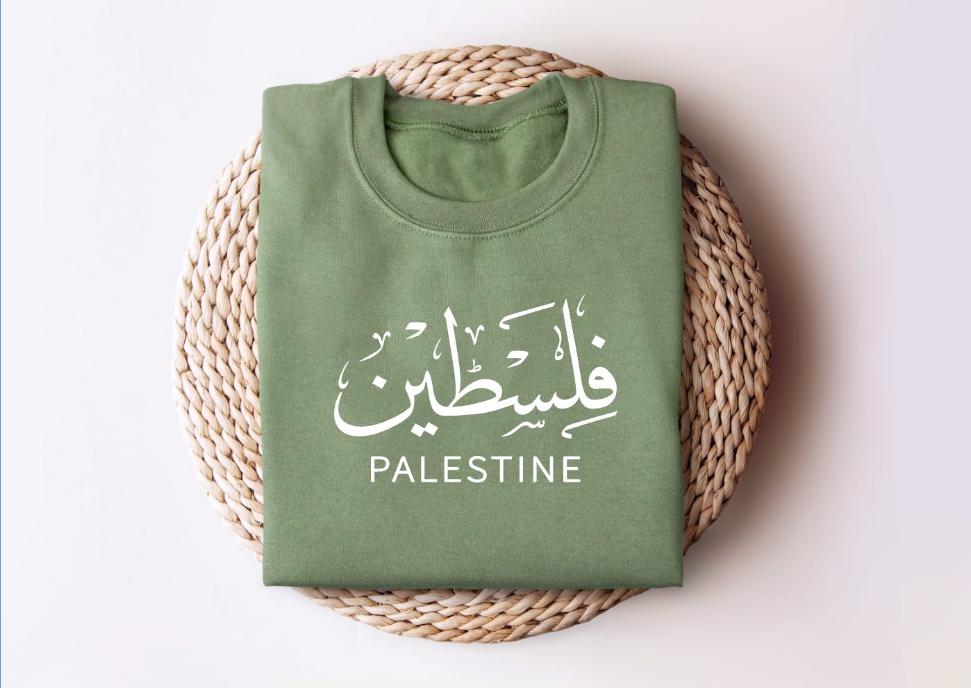 Palestine sweatshirt folded on wicker basket with "Falasteen" text in Arabic and English.