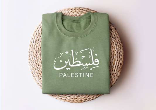 Palestine sweatshirt folded on wicker basket with "Falasteen" text in Arabic and English.